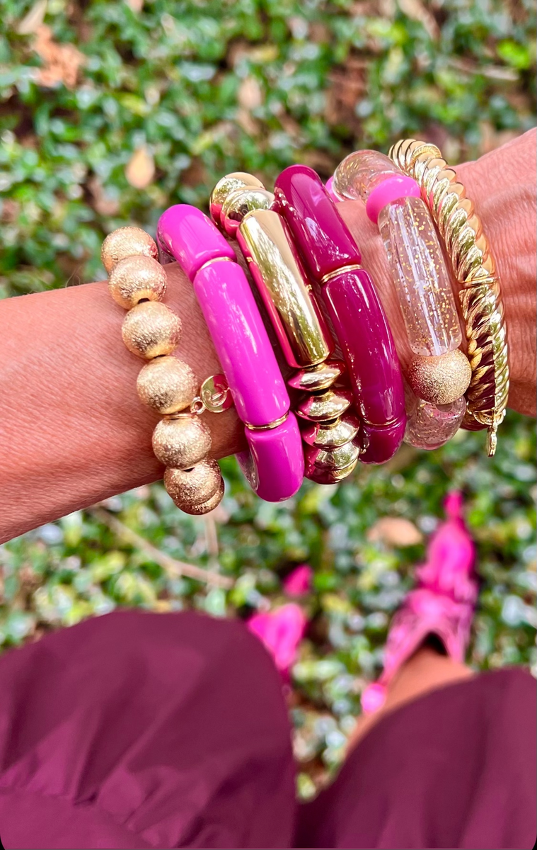 Playfully stacked bracelets in pink and gold, styled together to make the perfect stack.